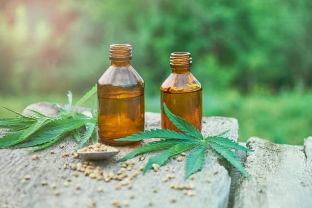 Hemp leaves on wooden background, seeds, cannabis oil extracts in jars.